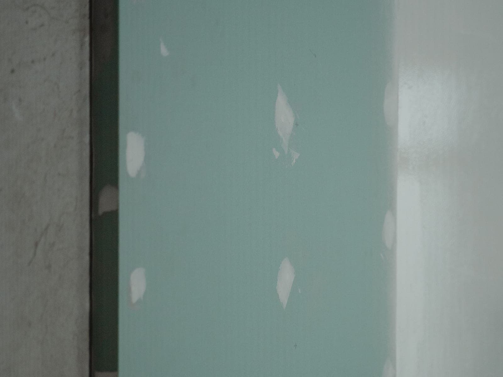 Plaques de plâtre hydrofuges vertes posées sur une cloison, joints enduits, avant carrelage