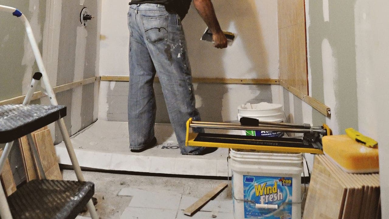 Plaquiste enduisant les joints de plaques hydrofuges dans une salle de bain en rénovation